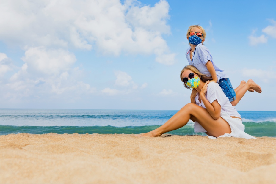 madre e hijo con mascarillas en la playa