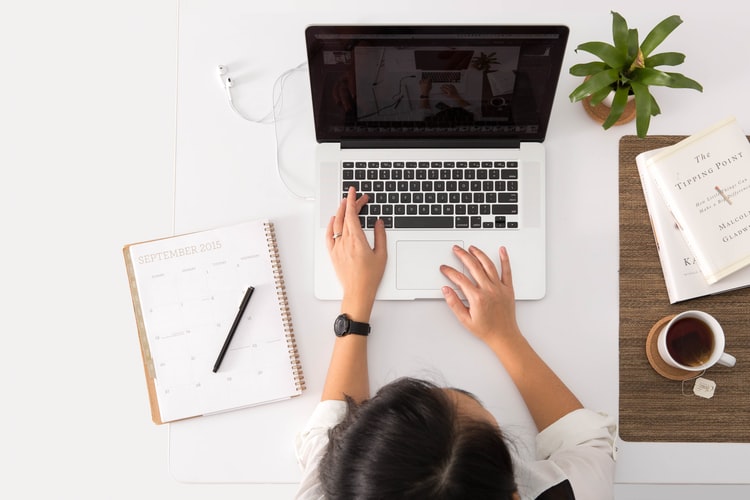 mujer estudiando en una laptop, vista desde arriba, escritorio OMT