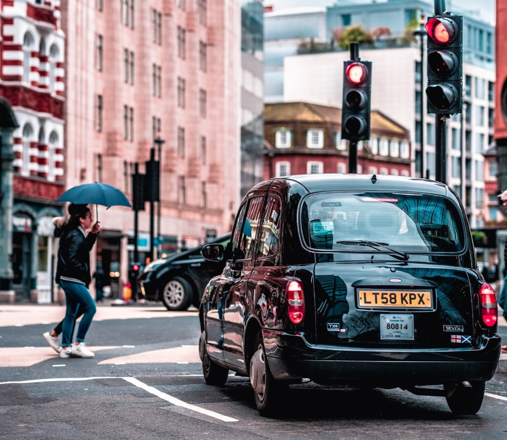 auto negro en una calle de Londres, un peatón y dos semáforos