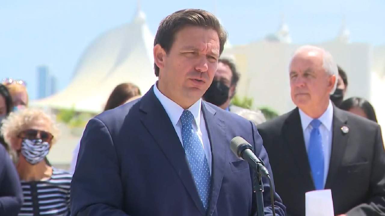 Ron DeSantis y personas detrás de él, bajo el sol