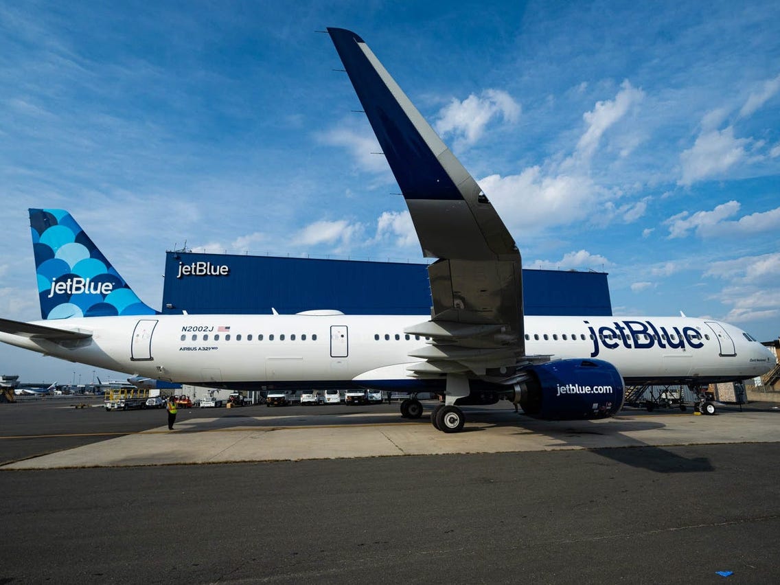 avión de JetBlue en la pista junto a un hangar de la compañía