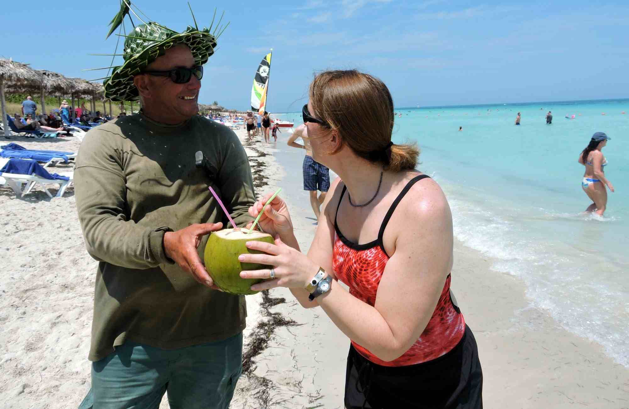 turista canadiense y un vendedor en una playa de Cuba, le entrega un coco