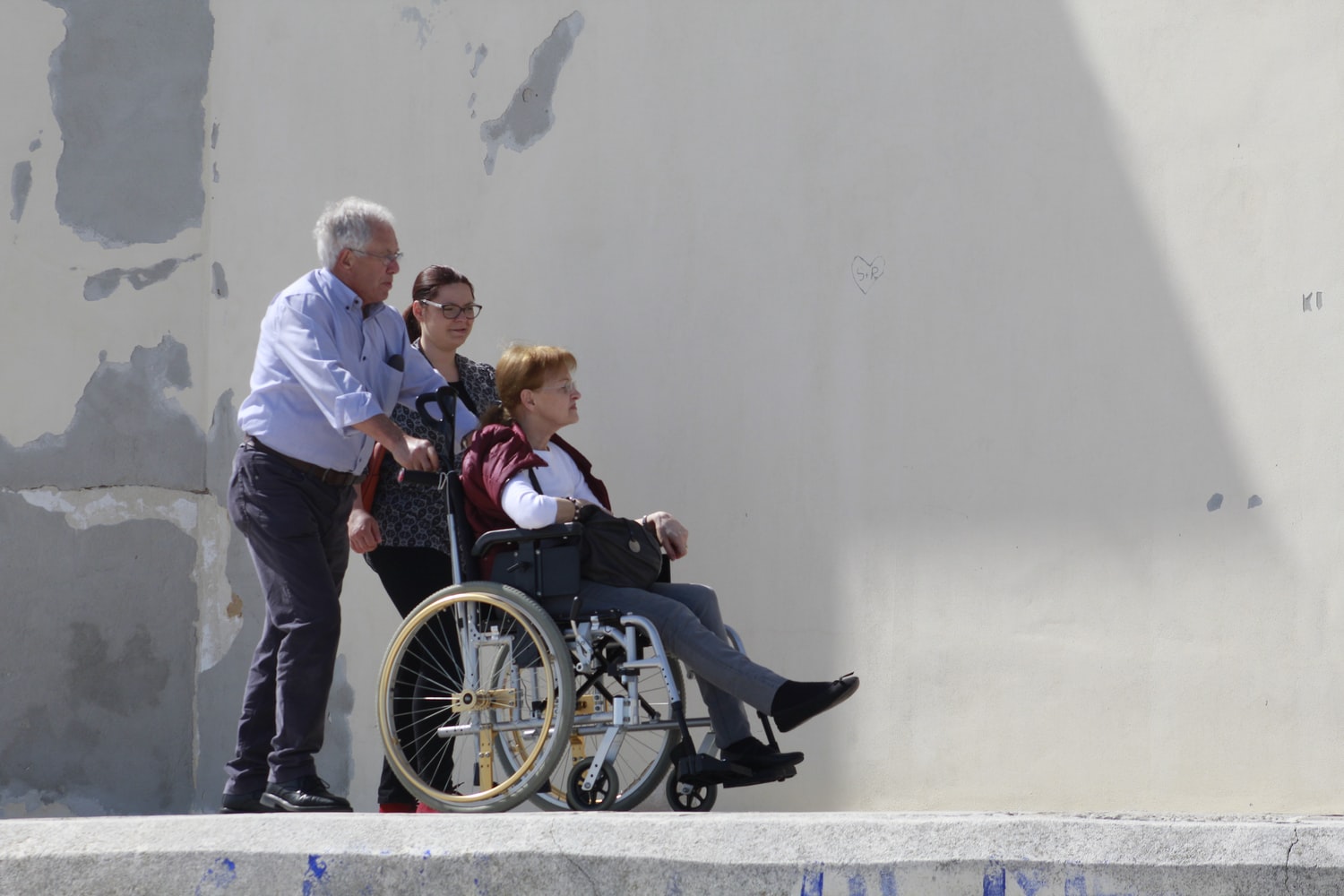 mujer en silla de ruedas, hombre y mujer detrás de la silla