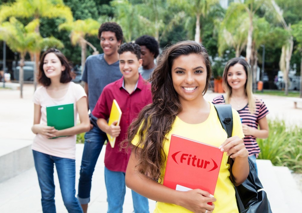 jóvenes y muchacha al frente con carpeta que dice FITUR