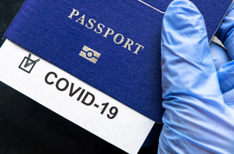 pasaporte y tarjeta Covid sostenido por un pulgar enguantado