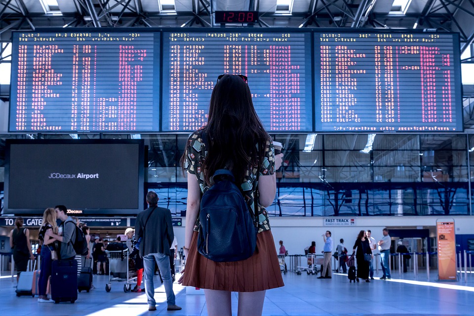 mujer frente a pantalla informativa en aeropuerto