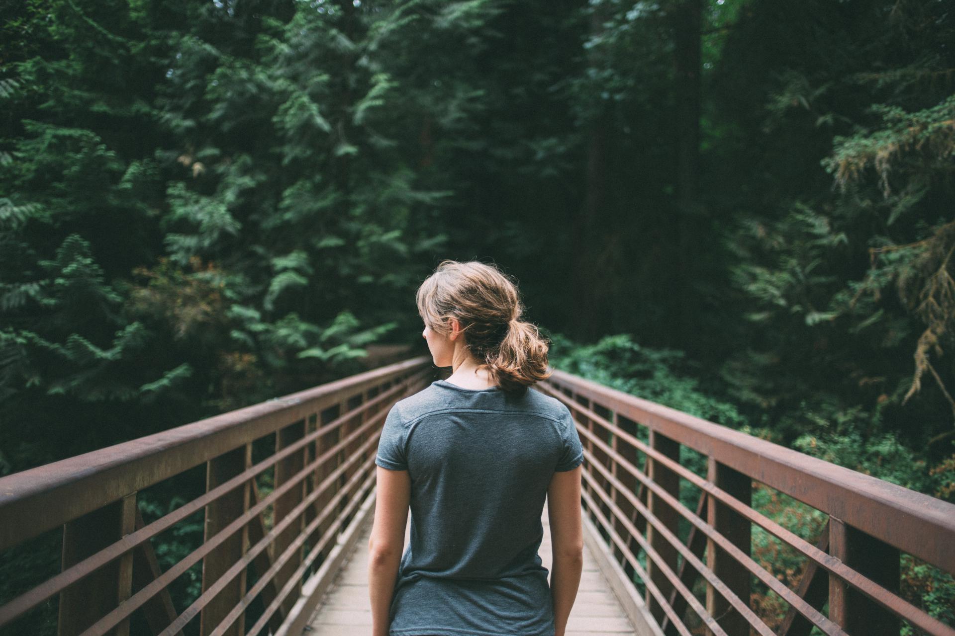 Mujer sobre un puente en el bosque