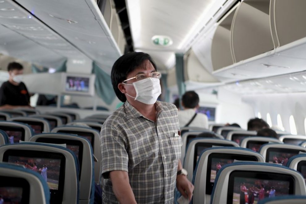 pasajero con mascarilla en el pasillo de un avión