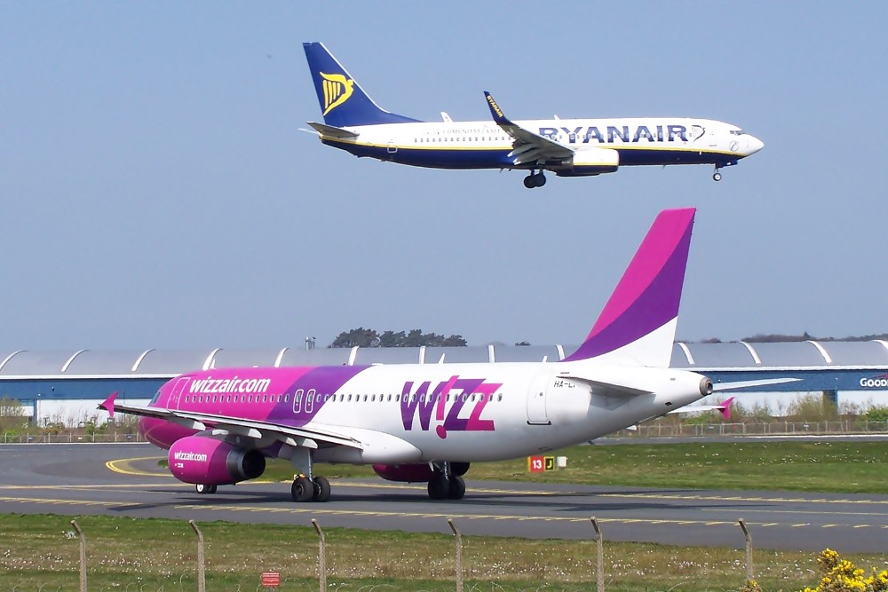 dos aviones, uno volando y el otro en la pista