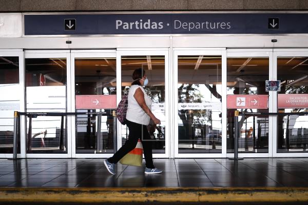 mujer con mascarilla pasa frente a la puerta de un aeropuerto