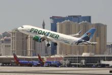 avión de Frontier Airlines despegando, edificios detrás